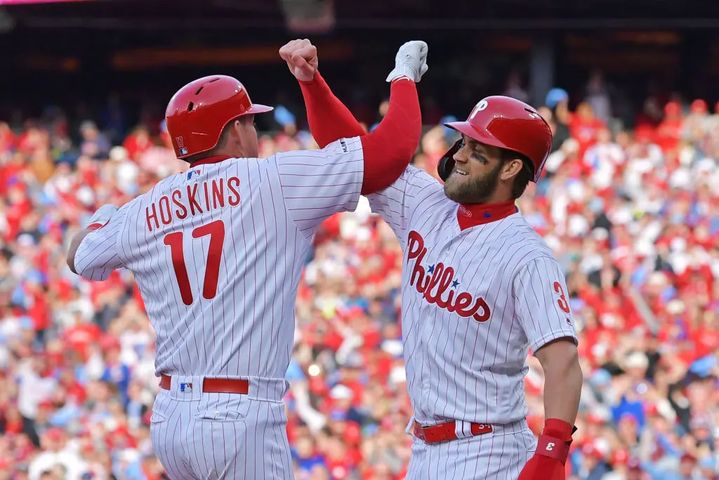 PHILADELPHIA, PA - MARCH 28: Rhys Hoskins #17 and Bryce Harper #3 of the Philadelphia Phillies celebrate Hoskins grand slam in the seventh inning against the Atlanta Braves on Opening Day at Citizens Bank Park on March 28, 2019 in Philadelphia, Pennsylvania