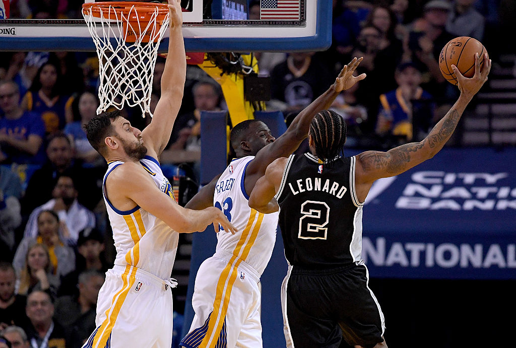 OAKLAND, CALIFORNIA - APRIL 07: Kawhi Leonard #2 of the San Antonio Spurs shoots over Draymond Green #23 and Andrew Bogut #12 of the Golden State Warriors in the first quarter of an NBA Basketball game at ORACLE Arena on April 7, 2016 in Oakland, California
