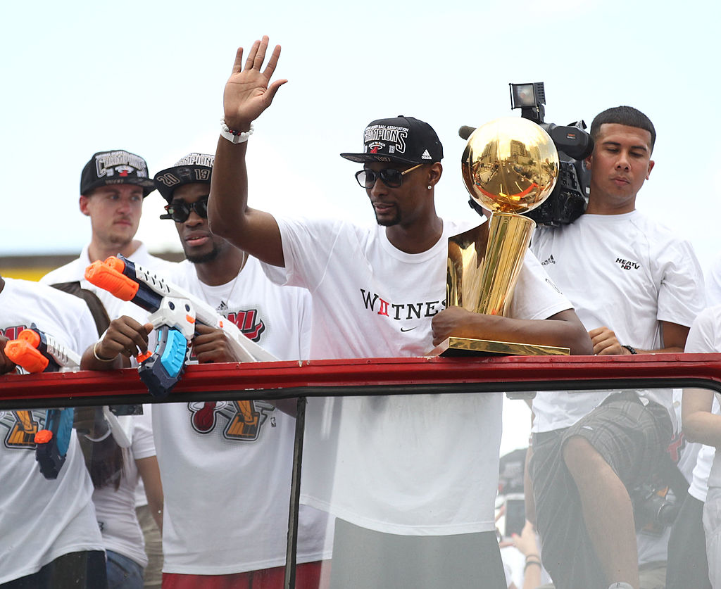 MIAMI, FL - JUNE 24: Forward Chris Bosh #1 of the Miami Heat holds the Larry O'Brien NBA Championship Trophy as he rides a bus during the championship victory parade on June 24, 2013 in Miami, Florida. The Miami Heat defeated the San Antonio Spurs in the NBA Finals