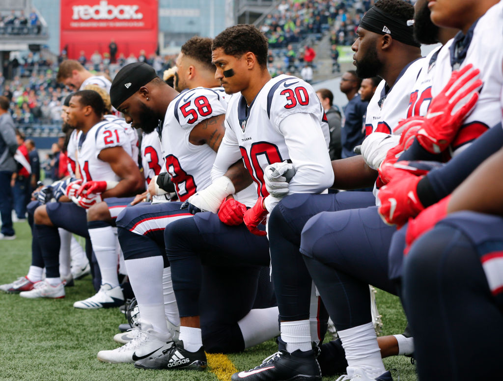 SEATTLE, WA - OCTOBER 29: Members of the Houston Texans, including Kevin Johnson #30 and Lamarr Houston #58, kneel during the national anthem before the game at CenturyLink Field on October 29, 2017 in Seattle, Washington. During a meeting of NFL owners earlier in October, Houston Texans owner Bob McNair said "we can't have the inmates running the prison," referring to player demonstrations during the national anthem.