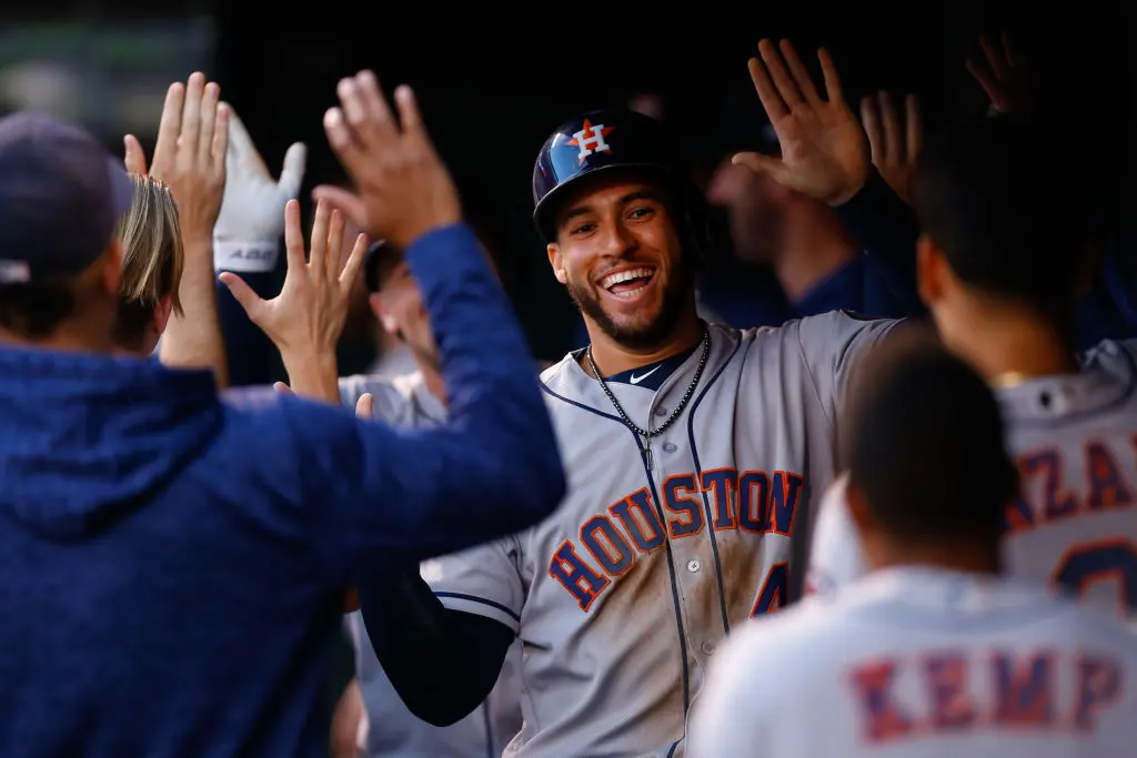 DENVER, CO - JULY 24: George Springer #4 of the Houston Astros celebrates in the dugout after scoring on a home run by teammate Alex Bregman in the first inning against the Colorado Rockies during interleague play at Coors Field on July 24, 2018 in Denver, Colorado