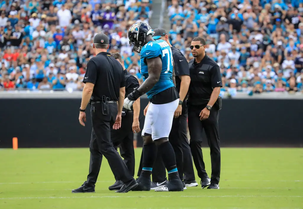 JACKSONVILLE, FL - SEPTEMBER 16: Cam Robinson #74 of the Jacksonville Jaguars is helped off the field by medical personal in the first half against the New England Patriots at TIAA Bank Field on September 16, 2018 in Jacksonville, Florida