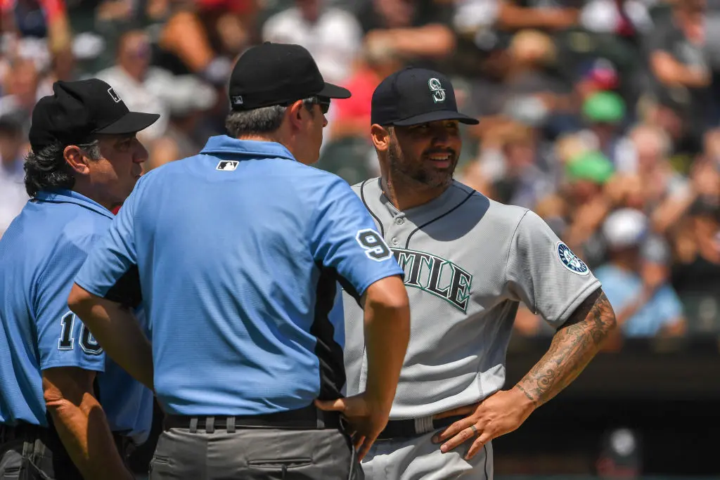 CHICAGO, ILLINOIS - JUNE 27: Umpires Phil Cuzzi #10 and Brian Gorman #9 talk to Hector Santiago #57 of the Seattle Mariners before ejecting him from the game after finding a substance on his glove in the fifth inning against the Chicago White Sox at Guaranteed Rate Field on June 27, 2021 in Chicago, Illinois. Today's game is a continuation from yesterday, which was suspended due to inclement weather
