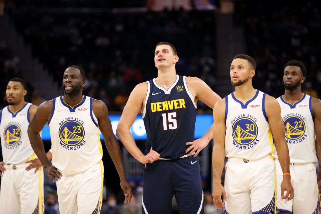 SAN FRANCISCO, CALIFORNIA - OCTOBER 06: Nikola Jokic #15 of the Denver Nuggets stands in between Otto Porter Jr. #32, Draymond Green #23, Stephen Curry #30 and Andrew Wiggins #22 of the Golden State Warriors during their game at Chase Center on October 06, 2021 in San Francisco, California