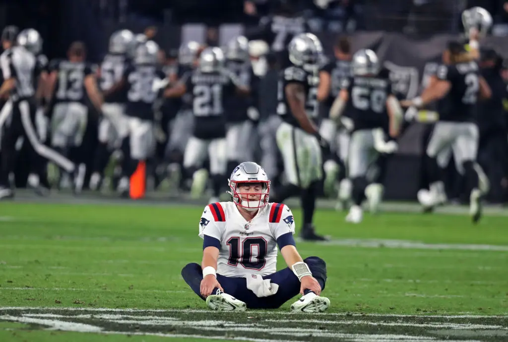 Paradise, NV - December 18: New England Patriots QB Mac Jones sits on the field with his eyes shut after the final play of the game. The Las Vegas Raiders defeated the Patriots, 30-24