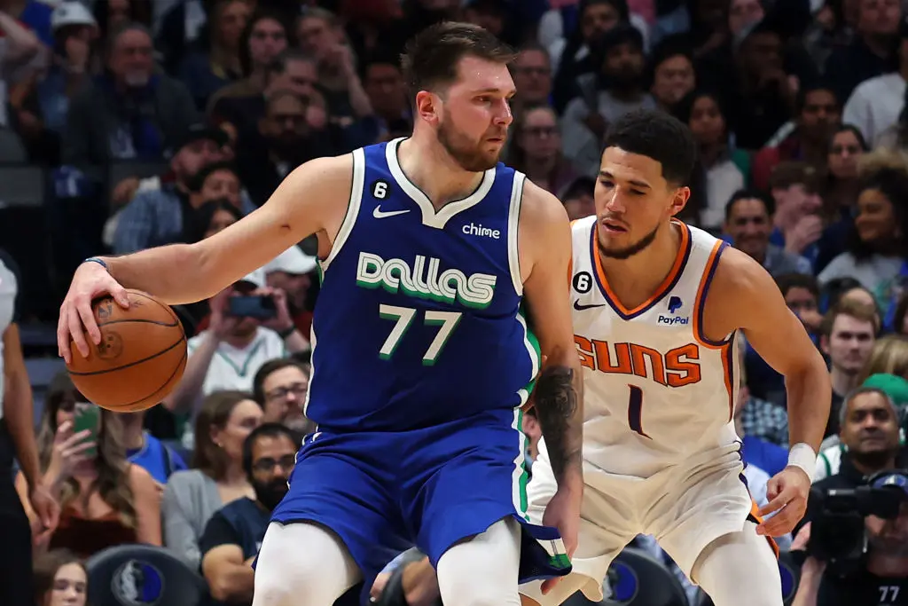 DALLAS, TEXAS - DECEMBER 05: Luka Doncic #77 of the Dallas Mavericks is guarded by Devin Booker #1 of the Phoenix Suns in the second half at American Airlines Center on December 05, 2022 in Dallas, Texas.