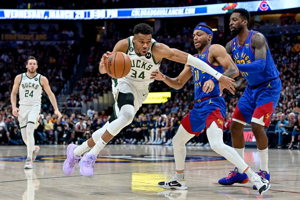 DENVER, CO - MARCH 25: Giannis Antetokounmpo #34 of the Milwaukee Bucks dribbles past Bruce Brown #11 and Jeff Green #32 of the Denver Nuggets in the second half of a game at Ball Arena on March 25, 2023 in Denver, Colorado.